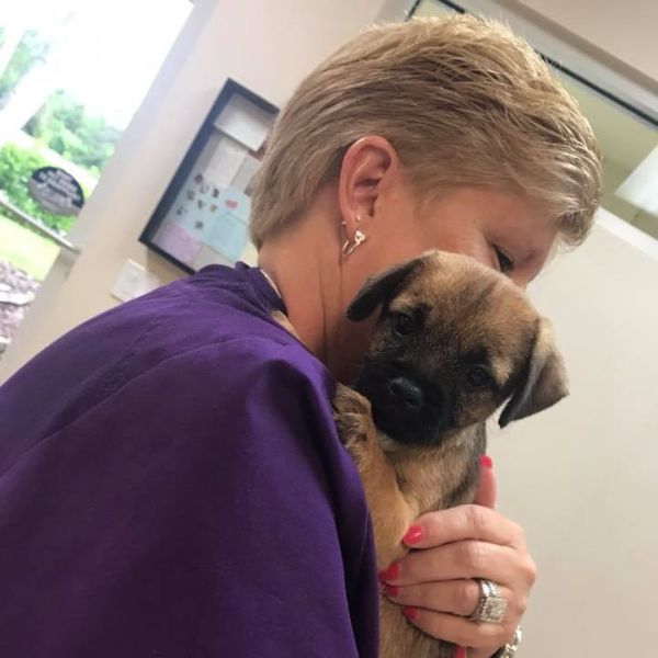 A woman gently cradles a small puppy in her arms